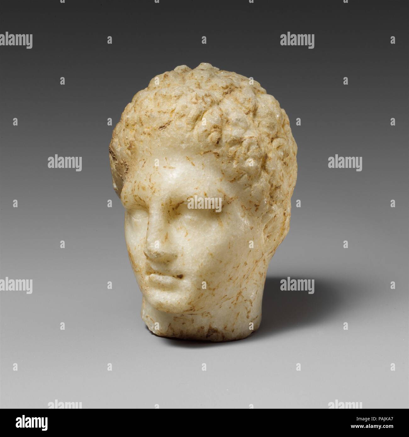 Marble head of a youth. Culture: Greek. Dimensions: H. 2 1/4 in. (5.7 cm.)  width 1 7/8 in. (4.8 cm.)  depth 2 in. (5.1 cm). Date: 4th century B.C..  Small marble head In the style of Praxiteles. Museum: Metropolitan Museum of Art, New York, USA. Stock Photo