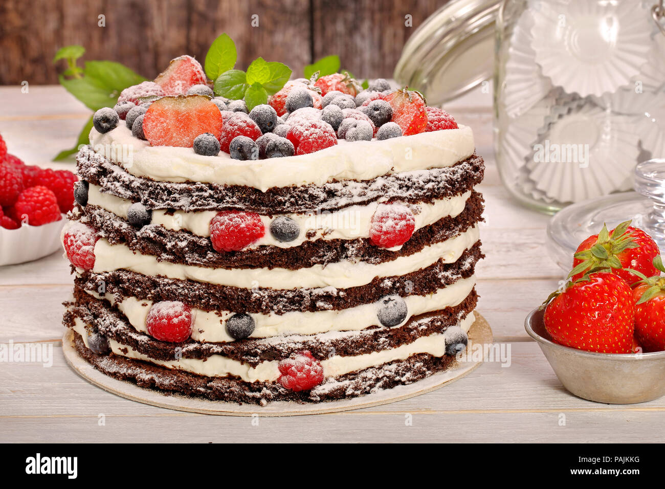 Chocolate cake with white cream and fresh fruits on wooden background Stock Photo