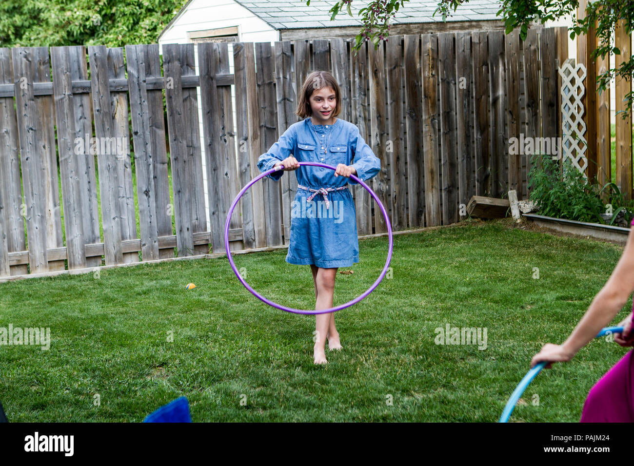 Young cute girl, in backyard, on the grass, play with hula hoop. Model  Release #104 Stock Photo - Alamy