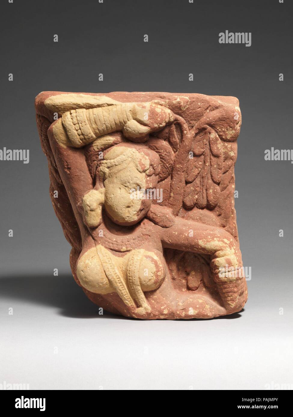 Tree Spirit Deity (Yakshi). Culture: India (Uttar Pradesh, Mathura region). Dimensions: H. 13 3/4 in. (34.9 cm); W. 12 1/2 in. (31.8 cm); D. 5 in. (12.7 cm). Date: 1st-2nd century.  This double-sided bracket (vrksadevata) for a gateway (torana) is decorated on either side with a tree-spirit deity known as a yakshi, who holds a flowering tree as a symbol of her fecundity. Her pose is that of salabhanjika ('breaking a branch of the sala tree'): grasping a branch, she thus engages with the fertility of the earth, bringing the tree into flower. Such figures provided an auspicious presence at the e Stock Photo