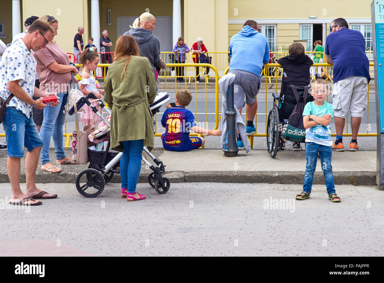 Small boy with arms folded while waiting for the carnival parade to start in Douglas, Isle of Man Stock Photo