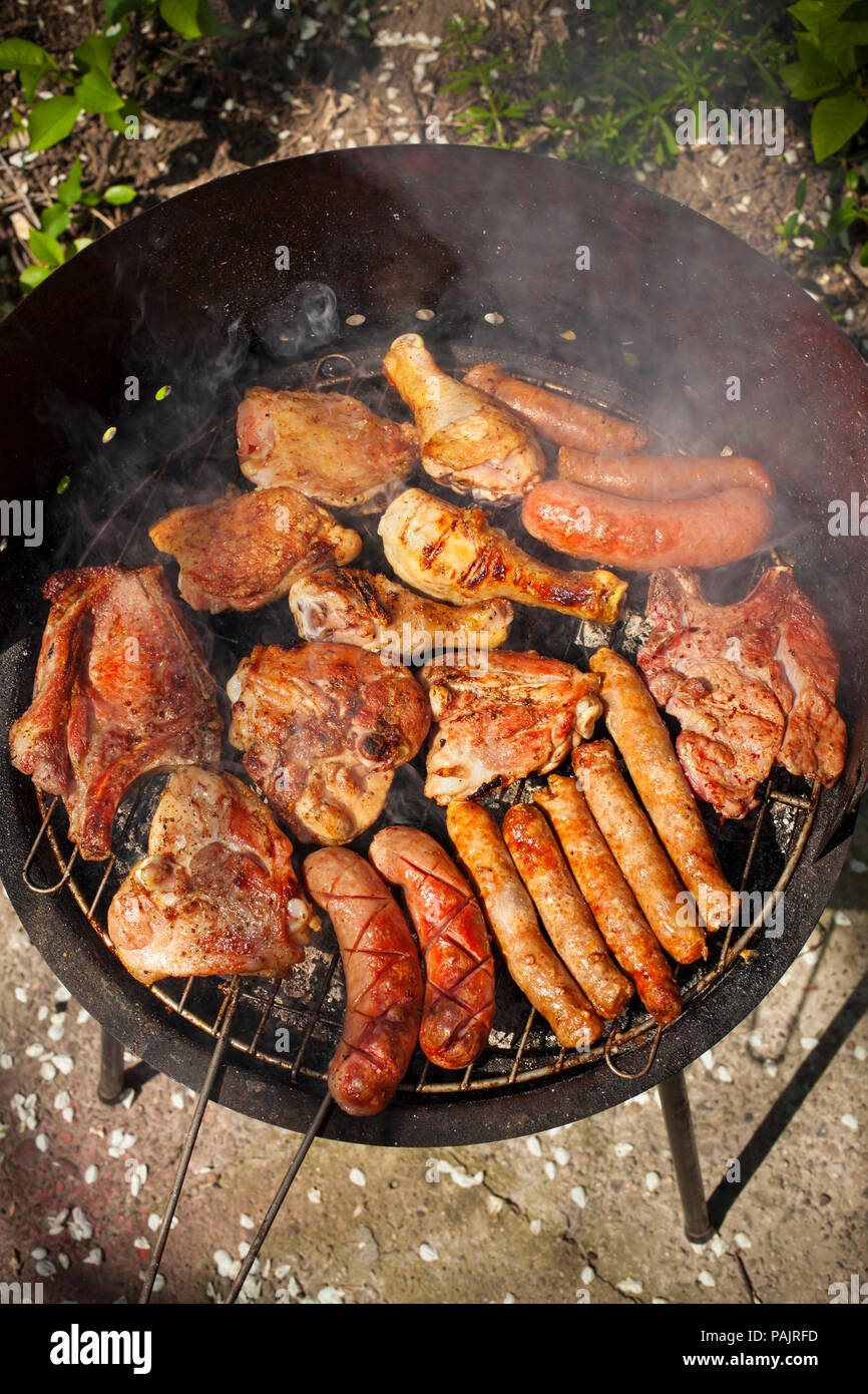 meat on barbecue, variety of meat on an outdoor, sunlit, smoking barbecue grill Stock Photo