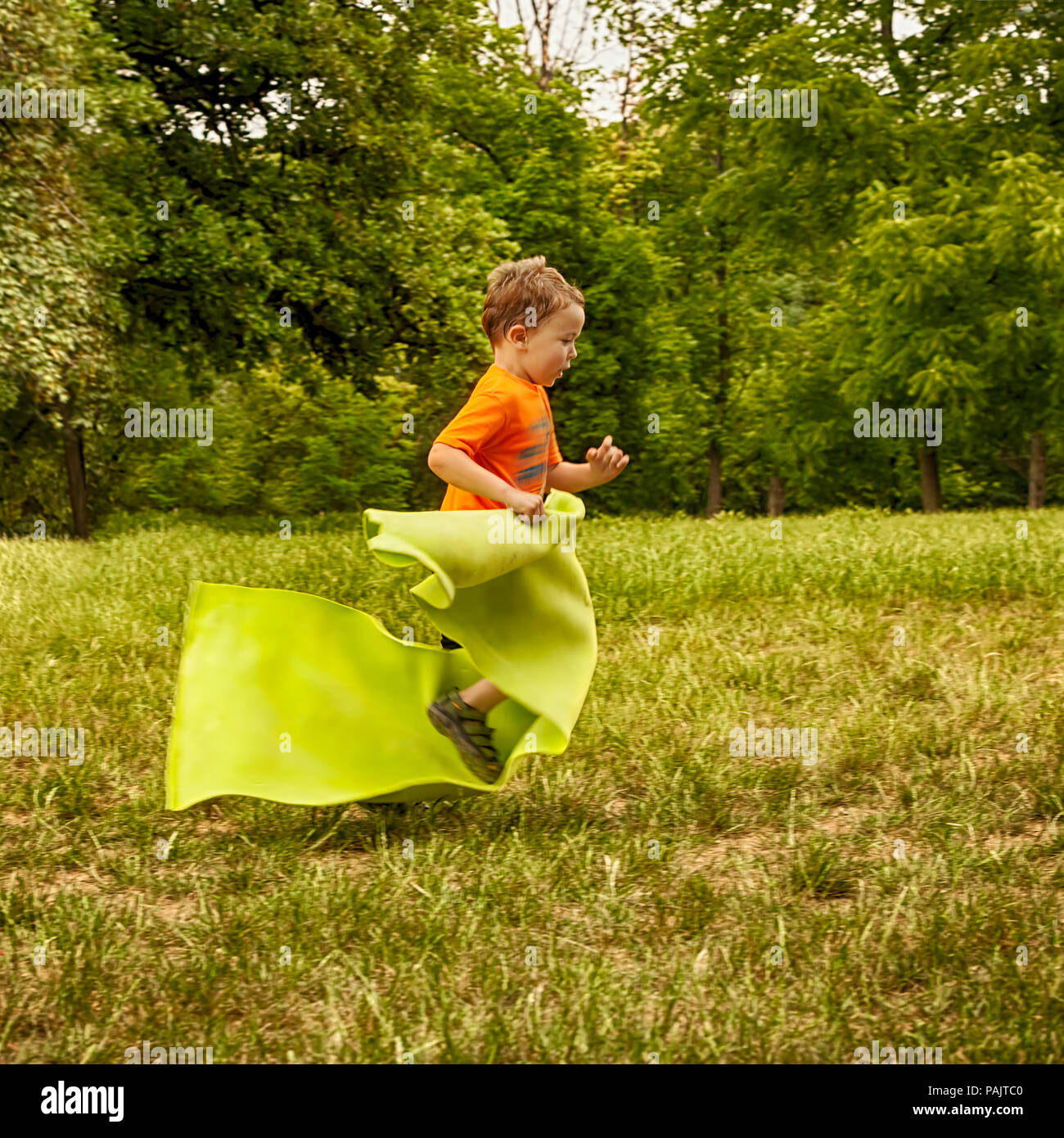 Happy child playing in the park running and carrying yoga mat Stock Photo