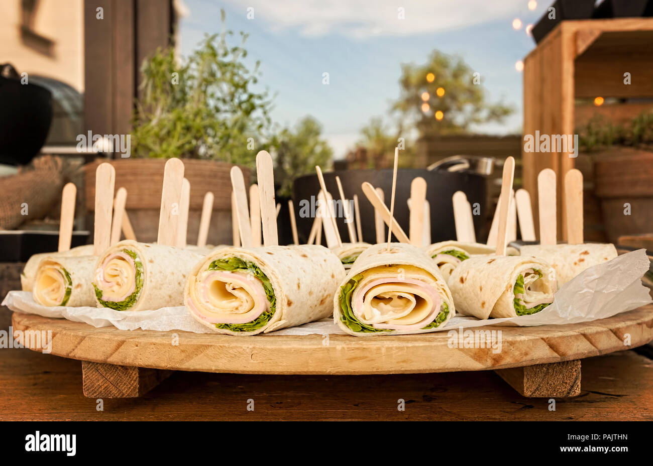 healthy turkey wrap sandwiches with lettuce, ham, cheese and cream servde in restaurant on a wooden board Stock Photo