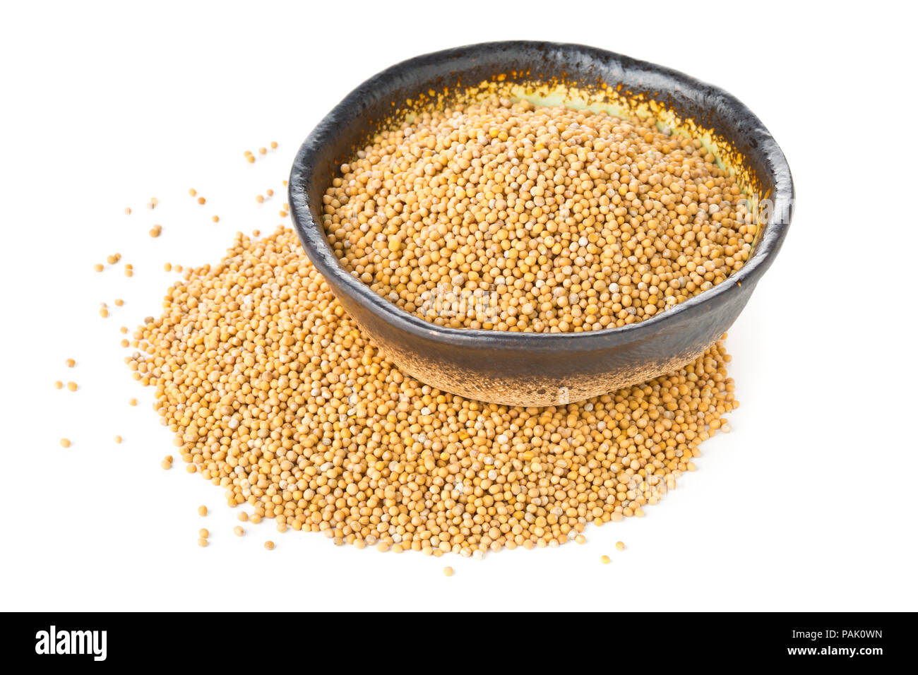 Heap of raw, unprocessed mustard seed kernels in bowl on white background Stock Photo
