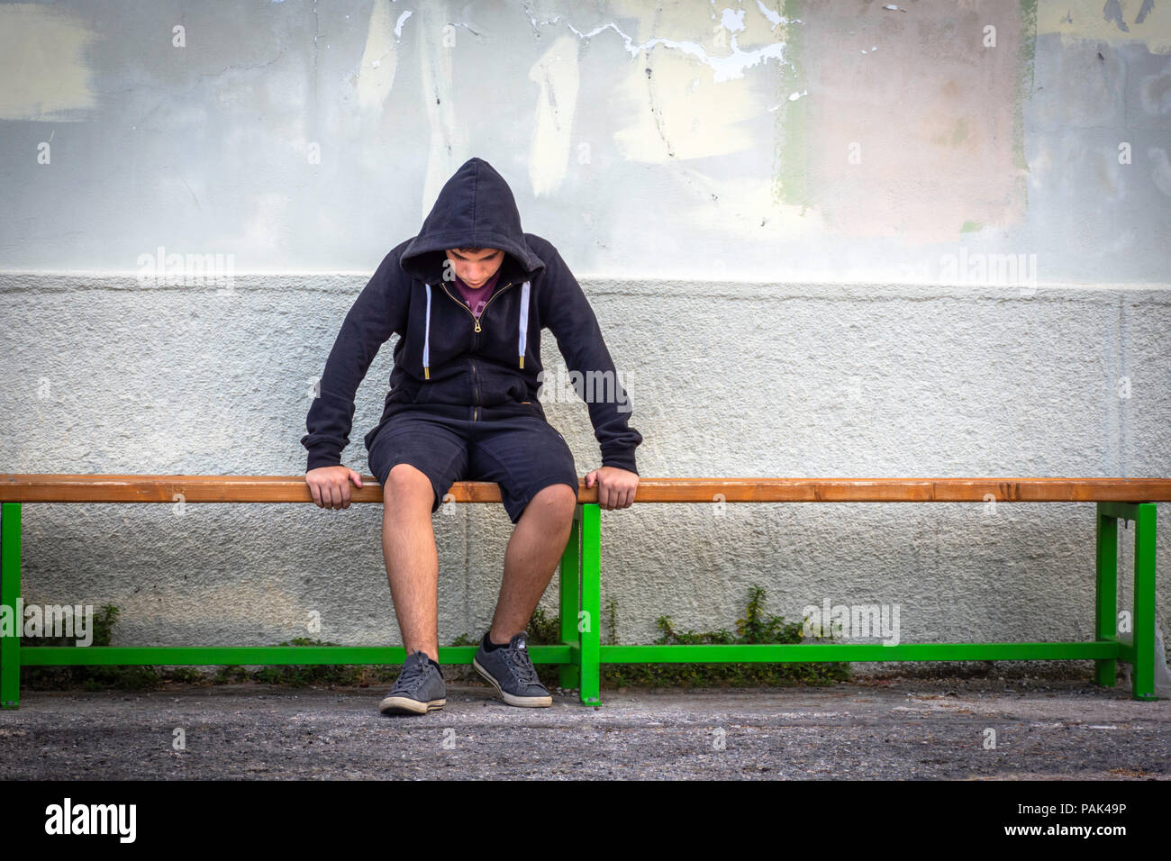 Little boy sad sitting alone at school hides his face Stock Photo