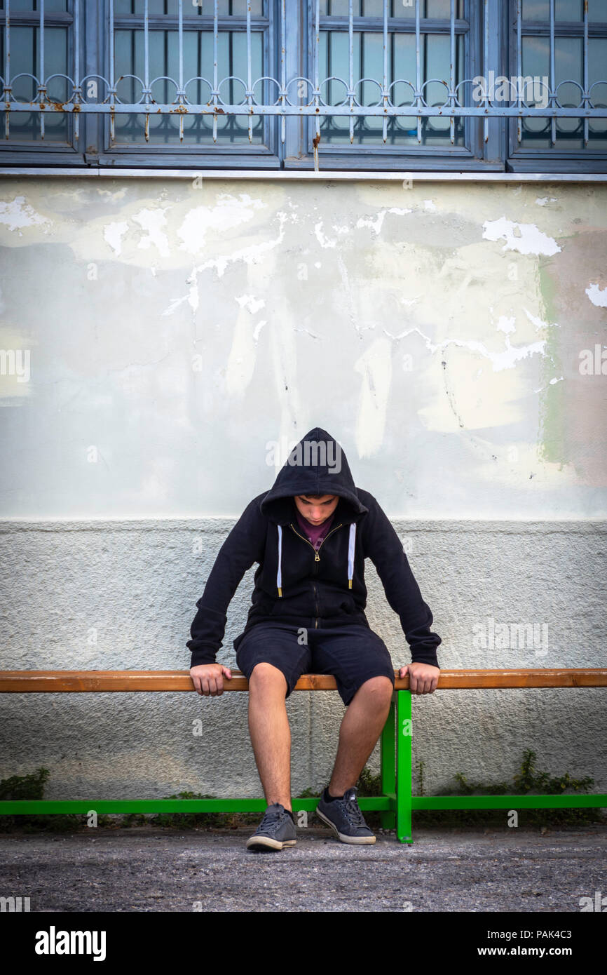 Little boy sad sitting alone at school hides his face Stock Photo