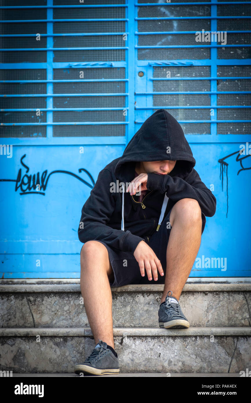 Little boy sad sitting alone at school hides his face Stock Photo