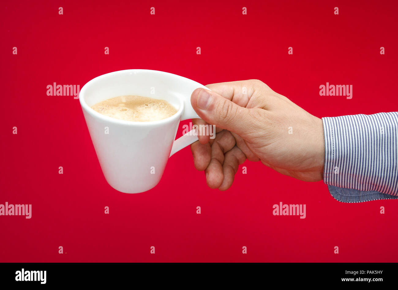 Dangers and health concerns of drinking too much coffee suggested by a white cup in a man's hand over a red alerted toxic background Stock Photo
