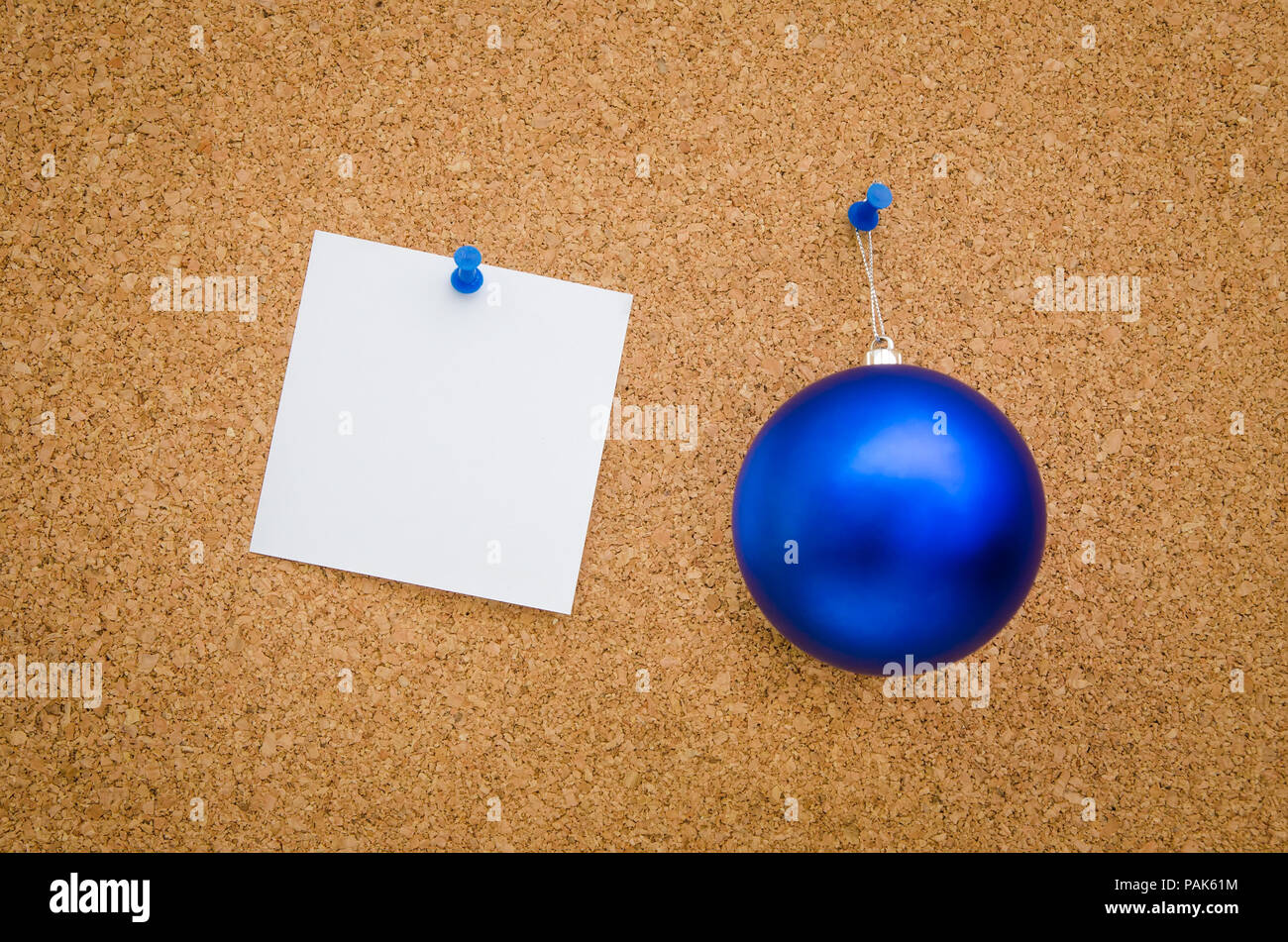 Blue christmas globe and white paper with text space pinned to a board suggesting a business office holiday christmas greeting card Stock Photo