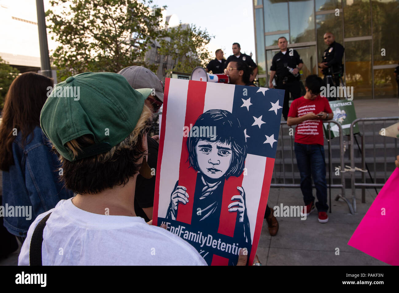 Los Angeles, USA - July 23 2018: Protestors rally outside LAPD headquarters while Incumbent L.A. County Sheriff Jim McDonnell and retired Lt. Alex Villanueva engaged in a contentious debate Monday in downtown Los Angeles on July 23rd, 2018. A protestor holds 'end family detention' sign in front of pol'ce off'cers (Credit: Aydin Palabiyikoglu/Alamy Live News Stock Photo