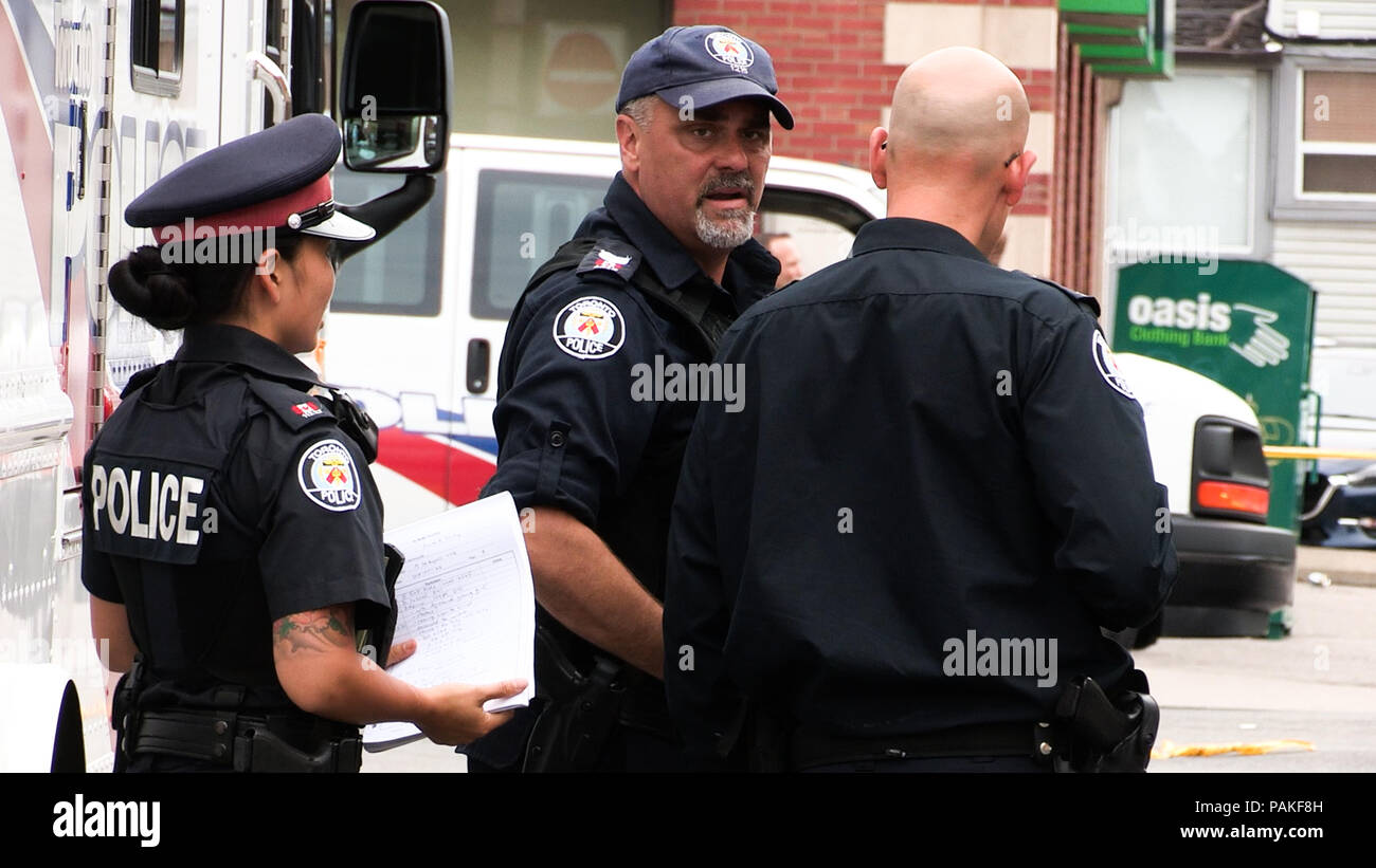Toronto, Canada. 23rd July, 2018. Local policemen search for evidence at the shooting scene in Toronto, Canada, July 23, 2018. An 18-year-old female university student and a 10-year-old girl were killed, and 13 others injured when a gunman opened fire in a busy Toronto street Sunday night. The suspected shooter, a 29-year-old Toronto man, also died. Credit: Li Haitao/Xinhua/Alamy Live News Stock Photo
