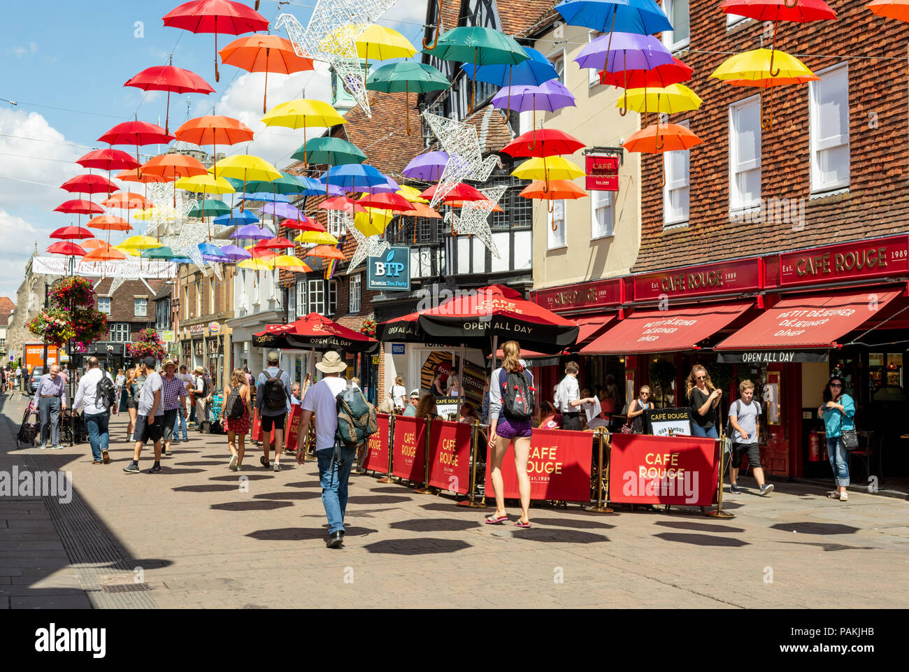 Salisbury, Wiltshire, UK, 24th July 2018, Weather: Hot and sunny in the cathedral city with temperatures edging towards 30 degrees. A colourful umbrella art installation casts octagonal shadows on the High Street. Stock Photo