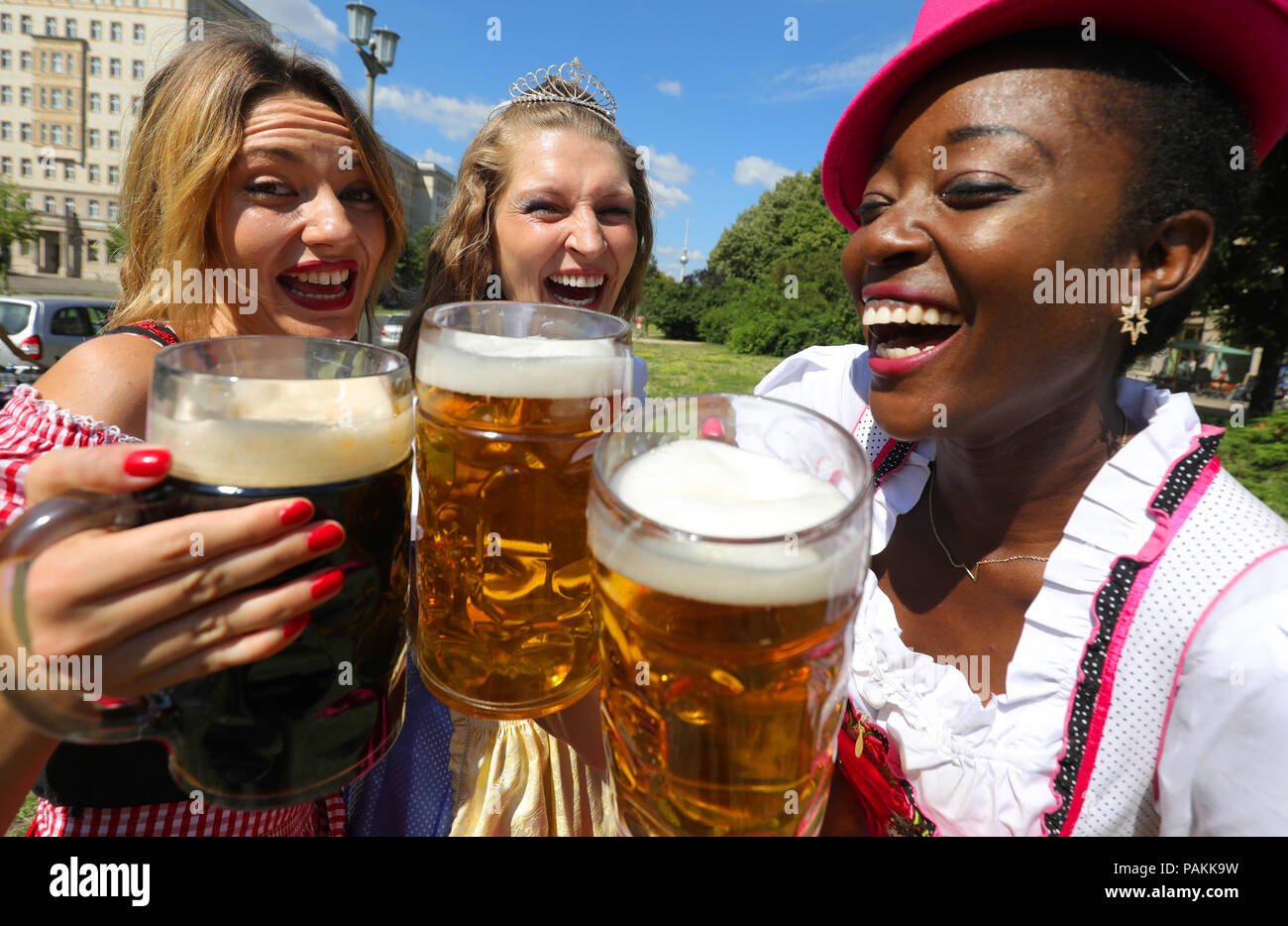24 July 2018, Germany, Berlin: Model Jacquline (L-R), Beer Queen Michaela and model Ayanna present steins with beer during a press event at the 22nd International Berlin Beer Festival on Karl-Marx-Allee in the district Friedrichshain-Kreuzberg. The beer festival will take place from 3 to 5 August 2018 between Frankfurter Tor and Strausberger Platz. Photo: Wolfgang Kumm/dpa Stock Photo