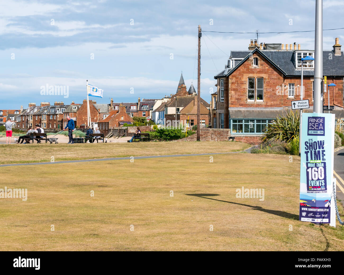 North Berwick, East Lothian, Scotland, United Kingdom, 24th July 2018. UK weather:  the sun is shining in the seaside resort on Elcho Green. A poster advertising North Berwick's Fringe by the Sea festival Stock Photo