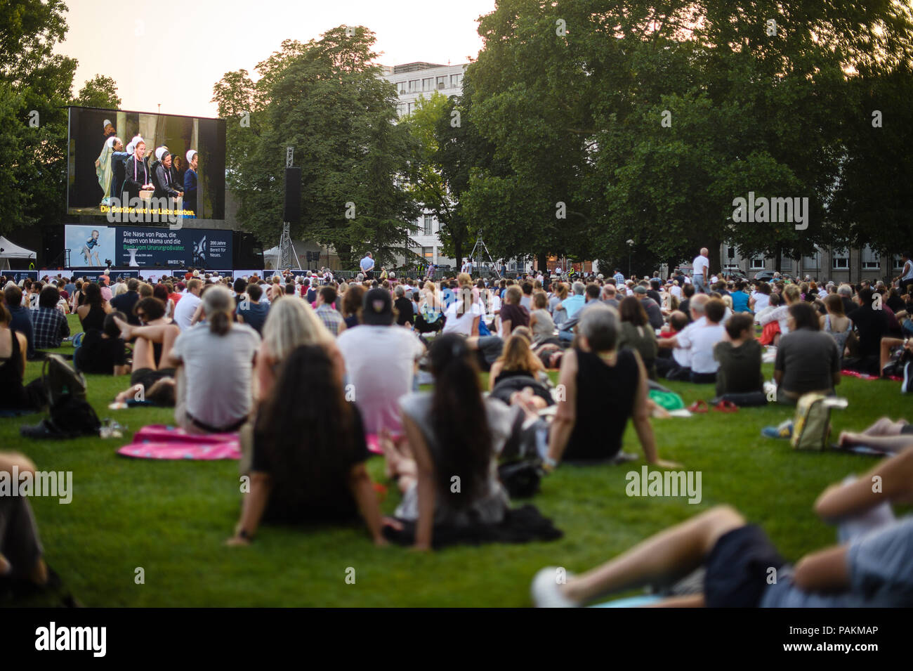 Stuttgart, Germany. 24th July, 2018. Visitors watch a live broadcast of Vincenzo Bellini's "Die Puritaner" (I puritani) from the Stuttgart Opera House during the open-air event "Oper am See" (lit. opera at the lake). Credit: Sebastian Gollnow/dpa/Alamy Live News Stock Photo