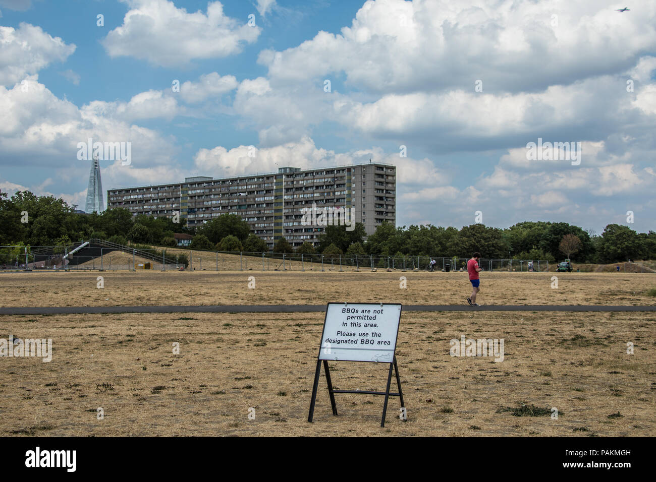 London,UK. 24 July, 2018. London gets some respite with some cloud but still no rain in parched South London where the grass in Burgess park looks more like sand with the Wendover block of the Aylesbury estate in the background with the Shard. David Rowe/Alamy Live News. Stock Photo