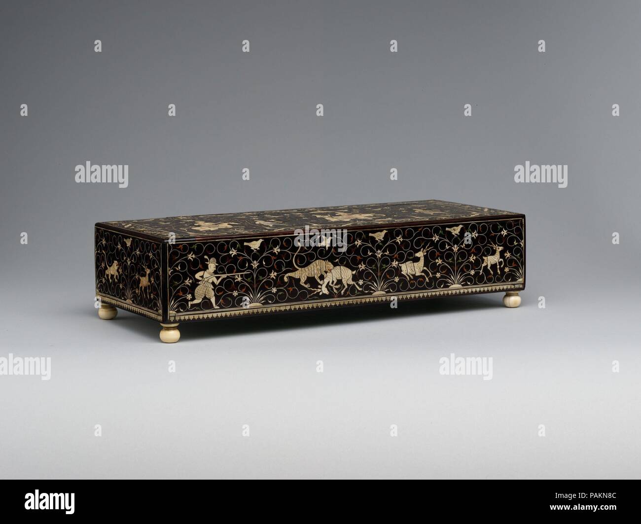 Inlaid Box for the Portuguese Market. Dimensions: H. 3 1/4 in. (8.3 cm)  W. 13 1/2 in. (34.3 cm)  D. 5 11/16 in. (14.5 cm)  Wt. 40.2 oz. (1139.8 g). Date: ca.1600.  From the late sixteenth century onward, Mughal India actively exported goods to Europe, particularly to Portugal, where such inlaid work was treasured. While many Europeanizing elements are evident in the decoration of this box, the hunting scenes were originally inspired by Persian compositions, which had in turn become popular in Mughal painting. The undulating branches of the bird-filled trees against which the European hunters  Stock Photo