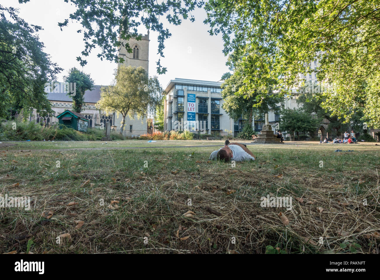 Man lying in a bristol park on a hot summers evening, July 2018, UK Stock Photo
