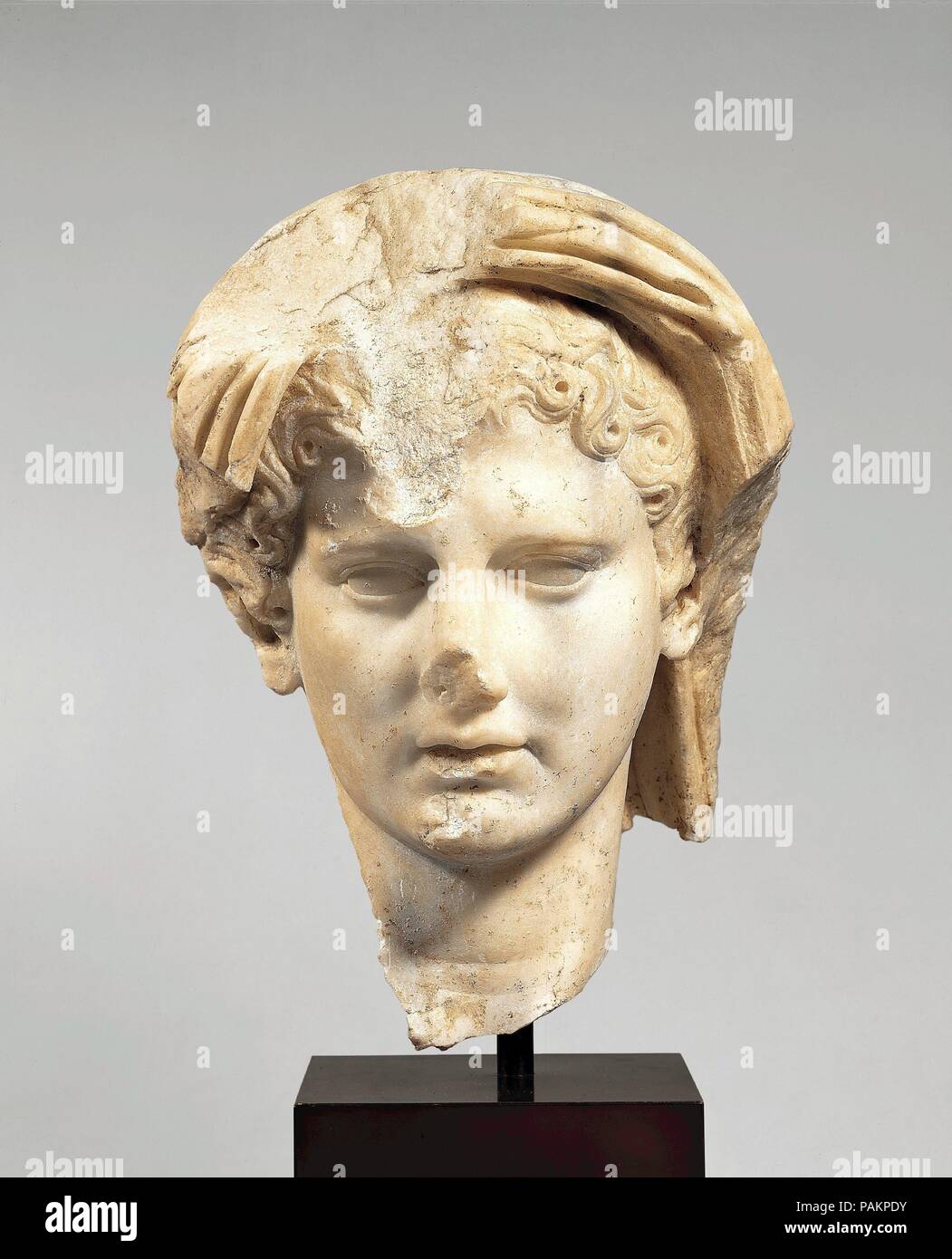 Marble head of a veiled man. Culture: Roman. Dimensions: H. 10 in. (25.4 cm). Date: 1st half of 1st century A.D..  The emperor was the chief state priest, and many statues show him in the act of prayer or sacrifice, with a fold of his toga pulled up to cover his head as a mark of  piety. However, this highly idealized head may represent the Genius, or protective spirit, of the living emperor. Traditionally the protective spirit of every Roman household was worshiped at the family shrine. It was represented by a statuette with veiled head holding implements of sacrifice. Similar veneration of t Stock Photo