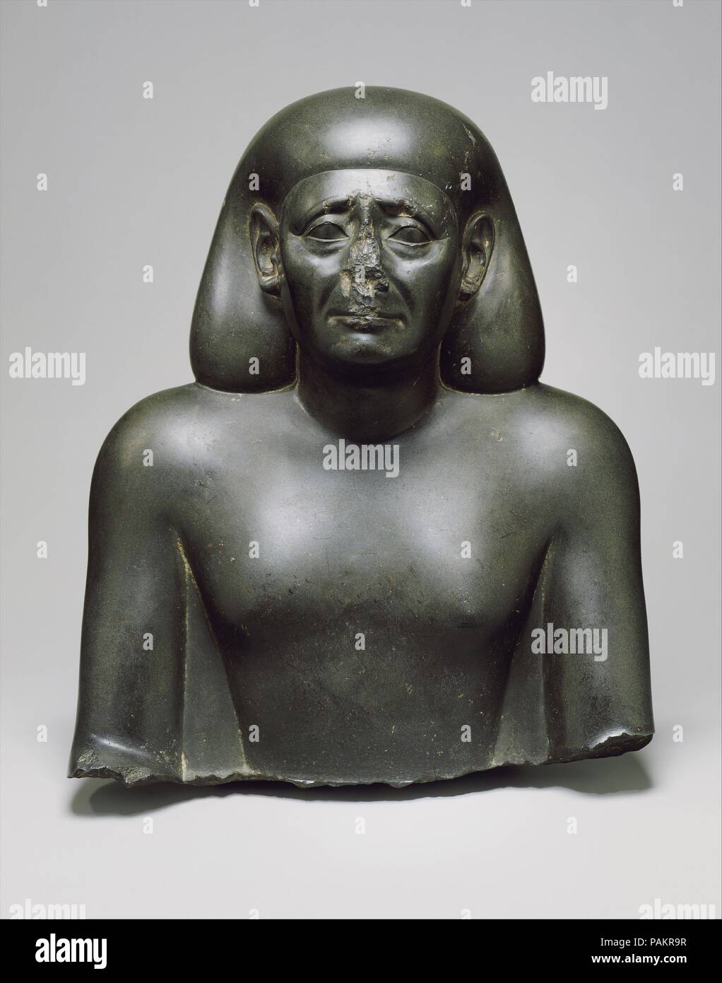 Bust of an Official. Dimensions: H. 38.1 × W. 30.1 × D. 17.3 cm, 22.1 kg (15 × 11 7/8 × 6 13/16 in., 48.8 lb.). Dynasty: Dynasty 30. Date: 380-342 B.C..  Only very occasionally do Egyptian statues convey a mood of sadness or concern like this one. This statue has plausibly been dated to the post-Persian Period where such features seem to fit best. The position of the arms and the lack of a back pillar suggest the original statue represented a cross-legged sitting official; if so, it would then be one of the several revivals in the fourth century of features that had gone out of vogue in early  Stock Photo