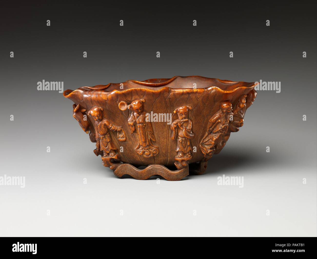 Cup with Eight Daoist Immortals. Culture: China. Dimensions: H. 3 1/8 in. (7.9 cm); W. (rim) 6 1/4 in. (15.9 cm); D. 3 1/2 in. (8.9 cm). Date: late 18th-19th century.  By the early thirteenth century a historical group of eight figures--six male, one female, and one hermaphrodite--had become symbolic of the attainment of immortality, one of the primary goals of Daoism. Each figure is a patron of a specific group and is identifiable by the object that he (or she) holds. For example, Lan Caihe, patron of gardeners and florists, carries a basket; He Xiangu, patron of housewives, holds a lotus; an Stock Photo