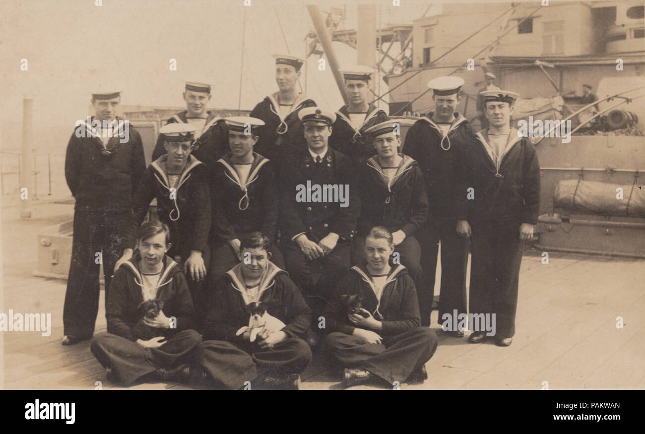 Vintage Photograph of Sailors From HMS Victorious. Three Sailors Holding Puppies. Stock Photo