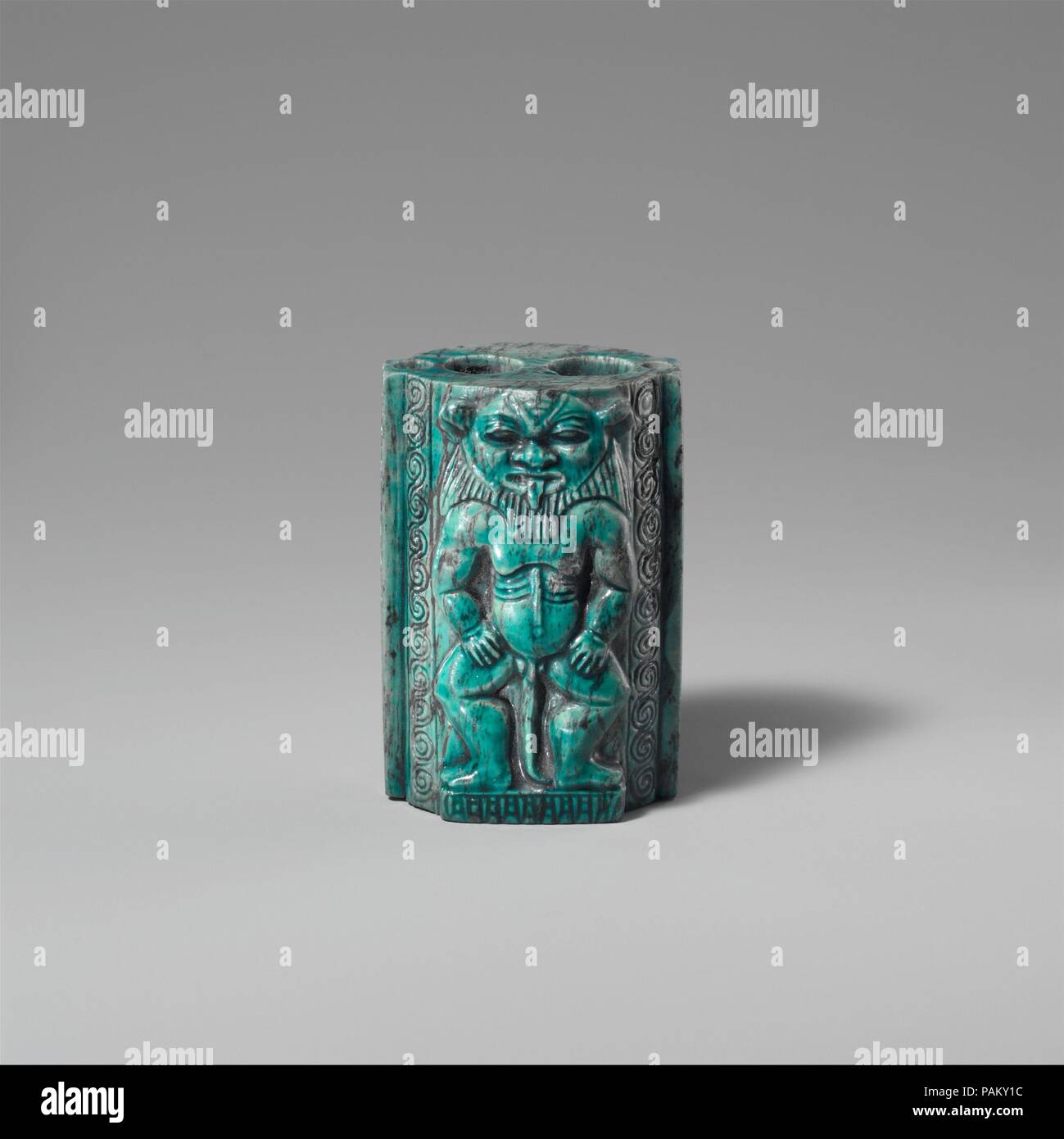 Kohl Container Decorated with Bes-images. Dimensions: H. 6 cm (2 3/8 in); w. 4 cm (1 9/16 in); d. 3.6 cm (1 7/16 in). Dynasty: mid-Dynasty 18. Date: ca. 1400 B.C..  As a measure for preventing disease, eye paint was second only to water in ancient Egypt. It was prepared from malachite and galena, ground on slate palettes, mixed with fat, and then applied around the eyes using a small stick, or applicator. Green eye paint, made from malachite, was primarily cosmetic. Galena is black in color, and the paint derived from it helped to reflect the glare of the Egyptian sun. More importantly, its le Stock Photo