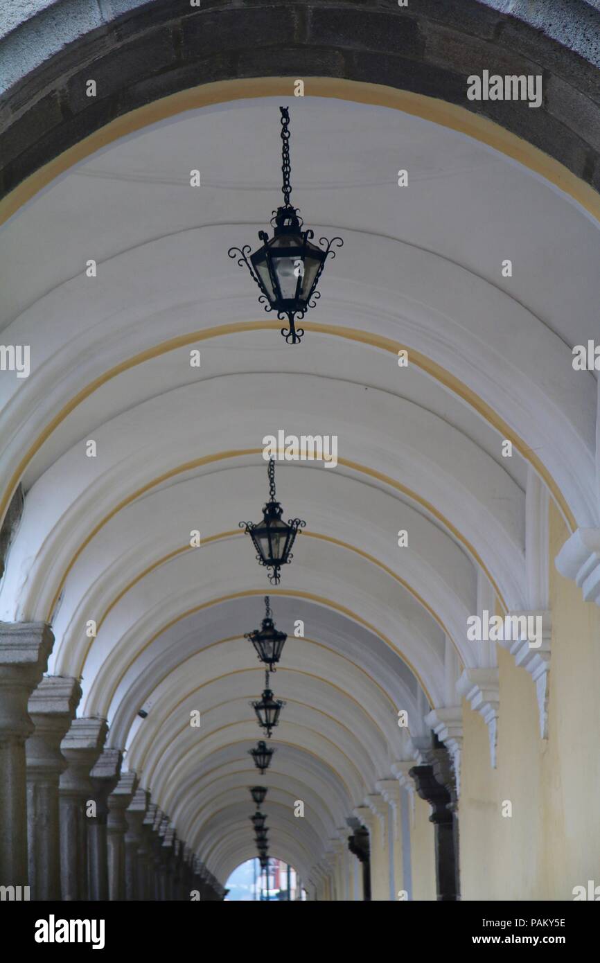 Undercover arched walkway with hanging metal lantern lamps Stock Photo