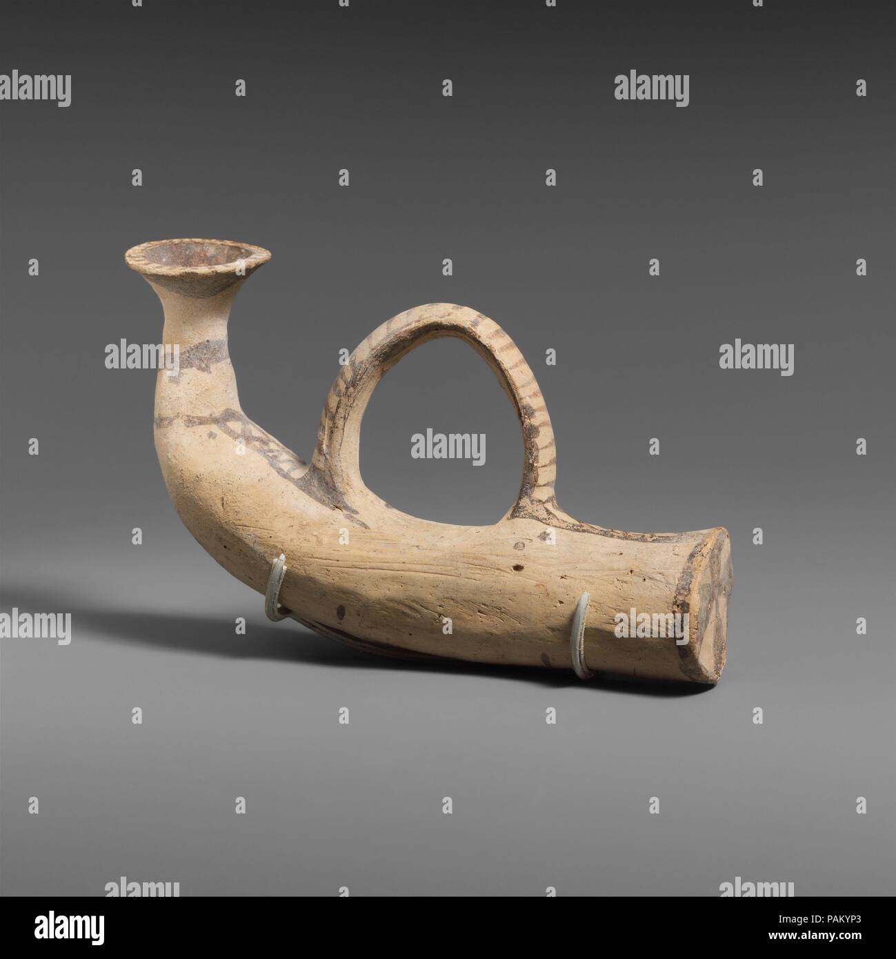 Terracotta vase in the shape of a horn. Culture: Cypriot. Dimensions: H. 3 11/16 in. (9.4 cm); length 6 5/16 in. (16 cm). Date: 1050-950 B.C..  An animal horn lends itself naturally for use in drinking and pouring libations, The clay version preserves details such as the articulated mouthpiece and the strap, here serving as a handle. Museum: Metropolitan Museum of Art, New York, USA. Stock Photo