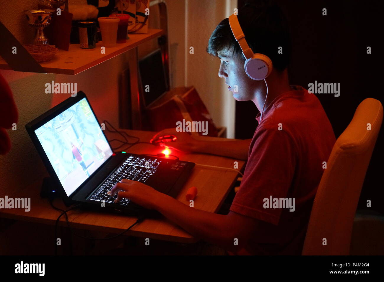 Milan, Italy - July 2018: Teenager playing Fortnite video game in the his bedroom by night. Stock Photo