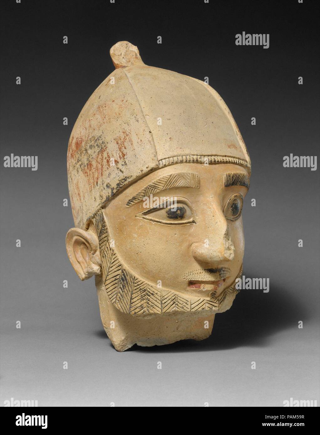 Terracotta head of a man. Culture: Cypriot. Dimensions: H. 11 1/2 in. (29.2 cm). Date: ca. 600 B.C..  The Cesnola Collection is fortunate to have two fine early heads that belonged to full-length figures. Large-scale terracotta sculpture began to be made on Cyprus during the mid-seventh century B.C. Molds were used for the heads, while the bodies were handmade. This bearded head wears the helmetlike headgear that appears on the nearby limestone sculptures. Details are articulated with considerable care, and remaining pigment suggests the liveliness of the figures' original appearance. Museum:  Stock Photo