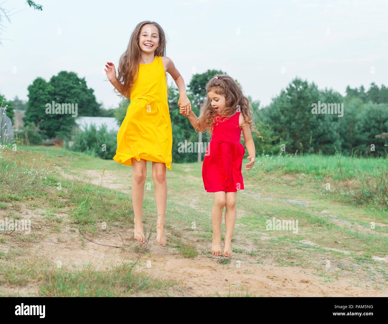 Two beautiful little girls is  jumping  at sunny summer day. Happy kids concept Stock Photo