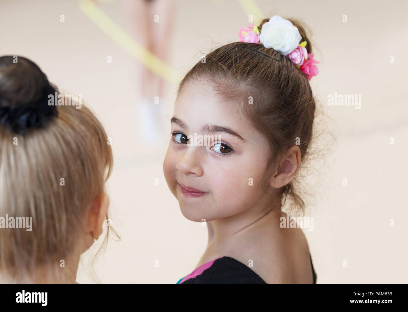 Little cute ballerina in studio looking on camera. Sport, training, fitness, stretching, dancing, yoga, active lifestyle concept Stock Photo