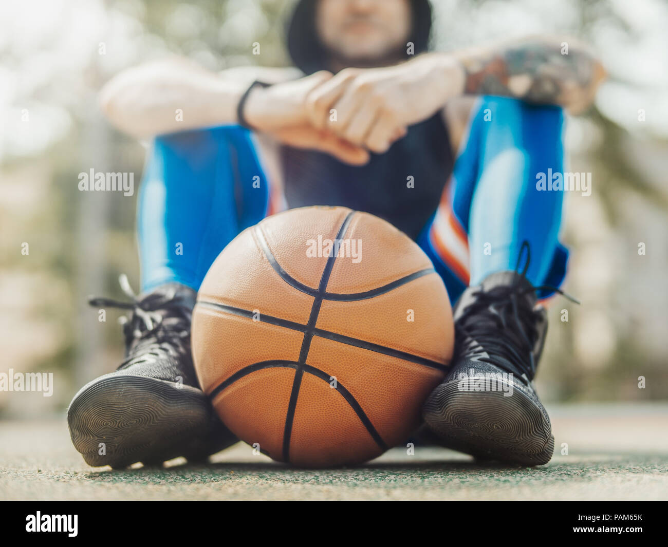 Close up of attractive man sitting on the court. Ball is on focus and foreground, man is on background and blurred. Stock Photo