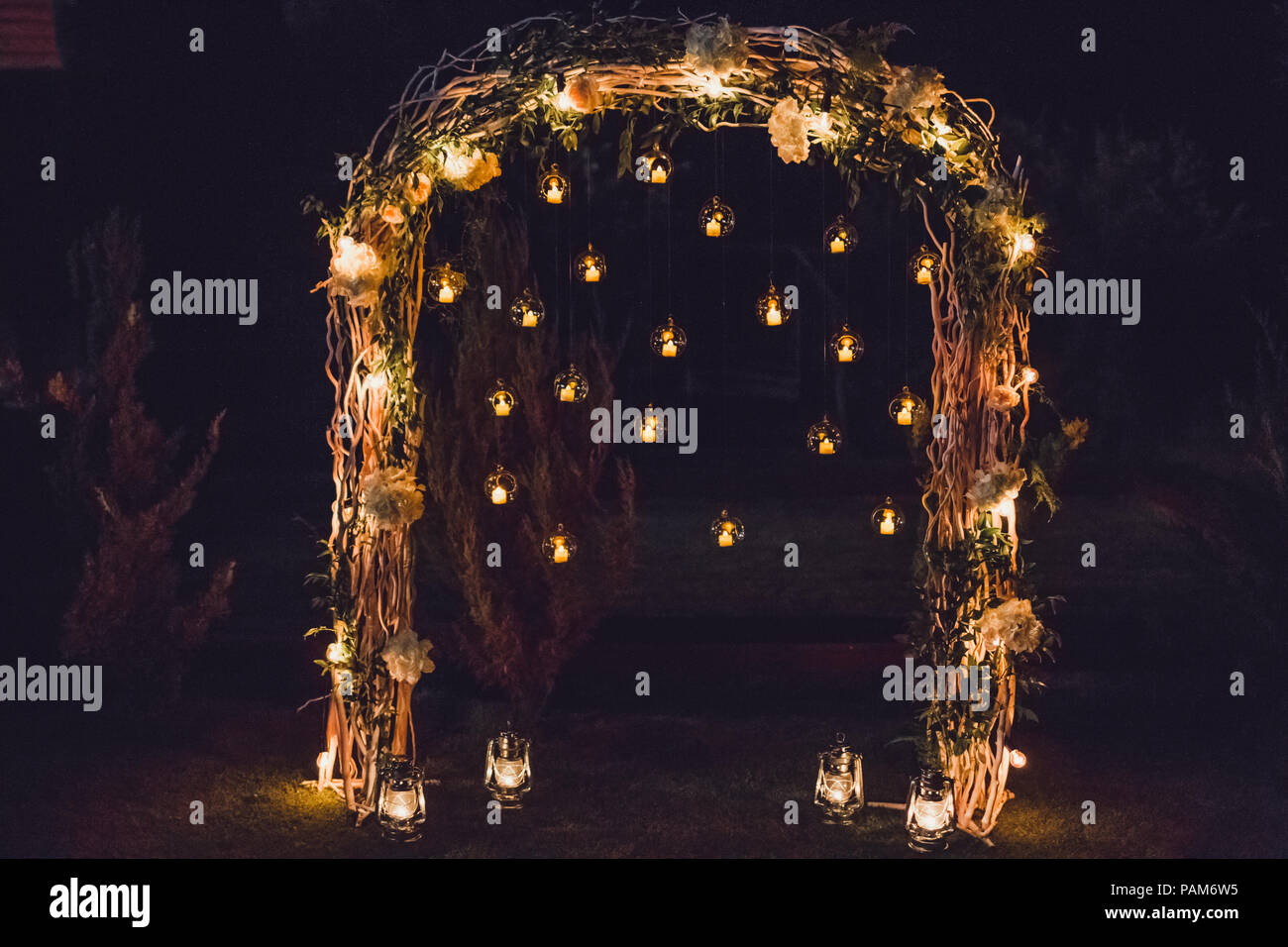 Night wedding ceremony, arch on party decorated with lights and candles in round glass spheres Stock Photo