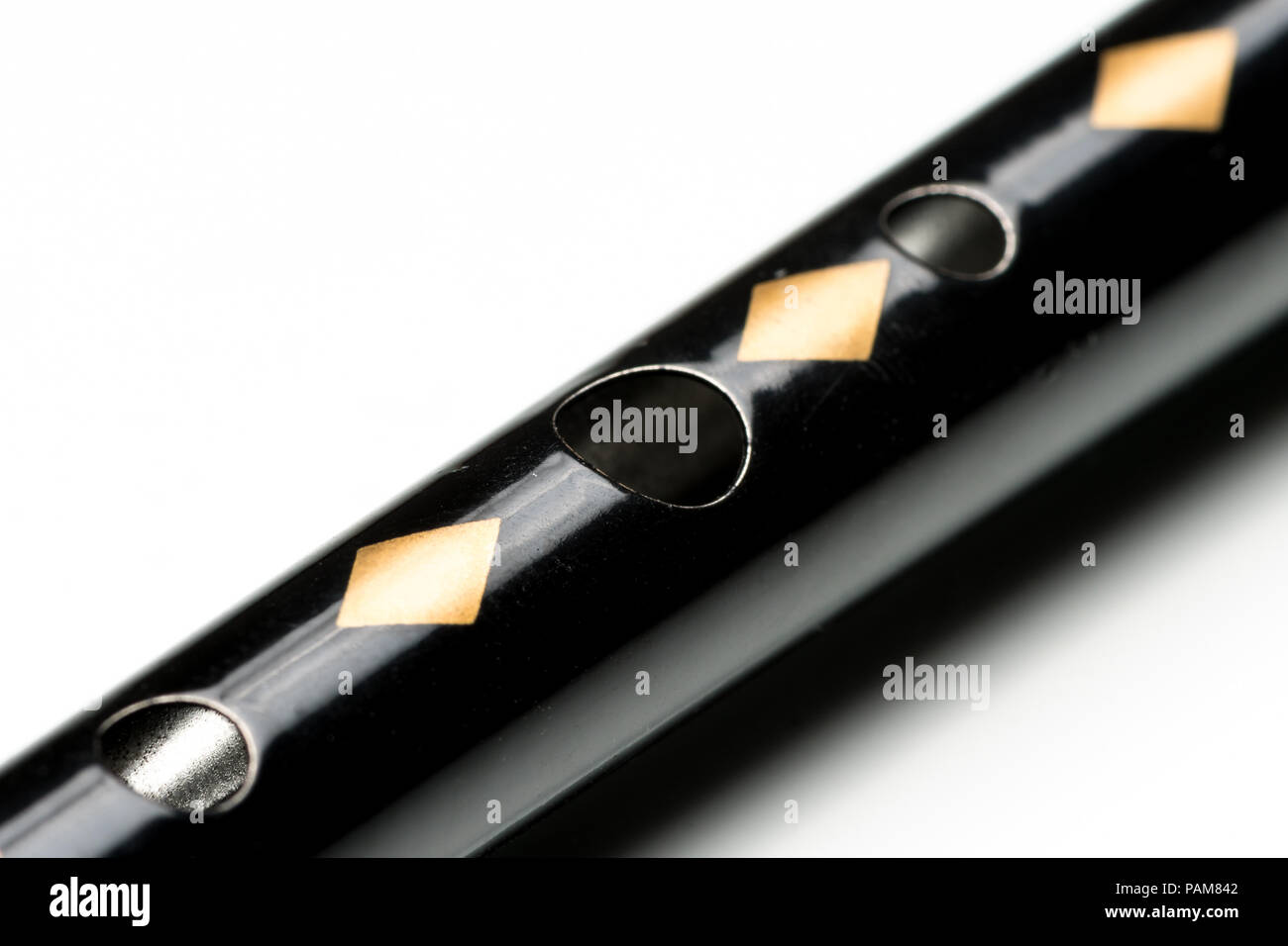 Details of a black tin whistle lying on a white reflective surface Stock Photo
