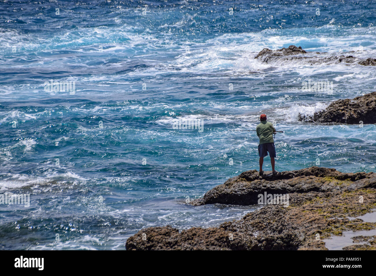 Man ocean fishing standing on coastline rocks Stock Photo - Alamy