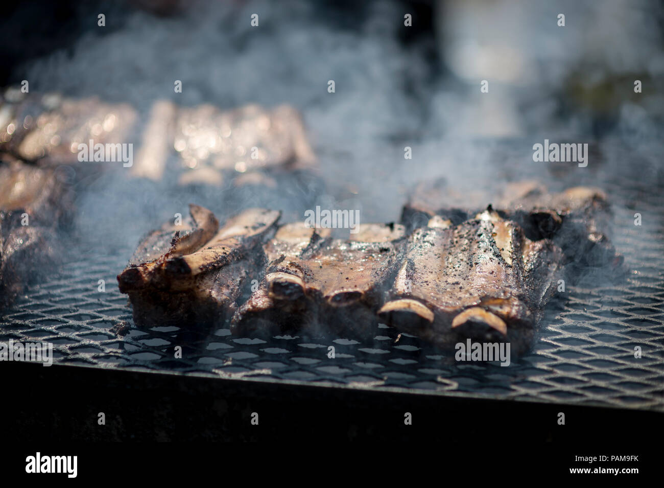 Ribs cooking on a smoky barbecue grill Stock Photo
