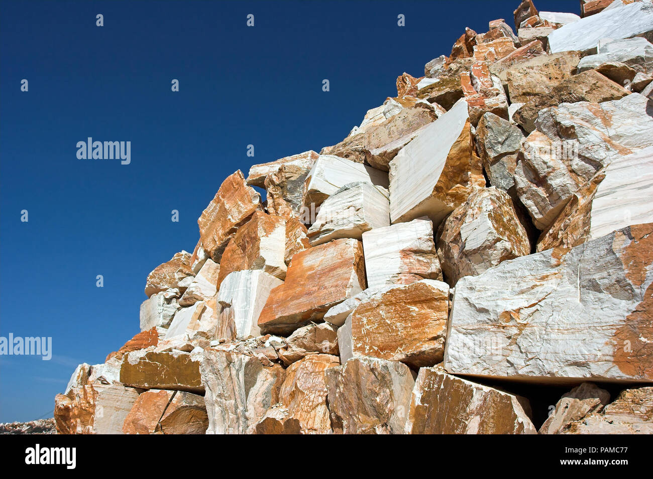 Big blocks of raw marble against deep blue sky in a quarry in south of