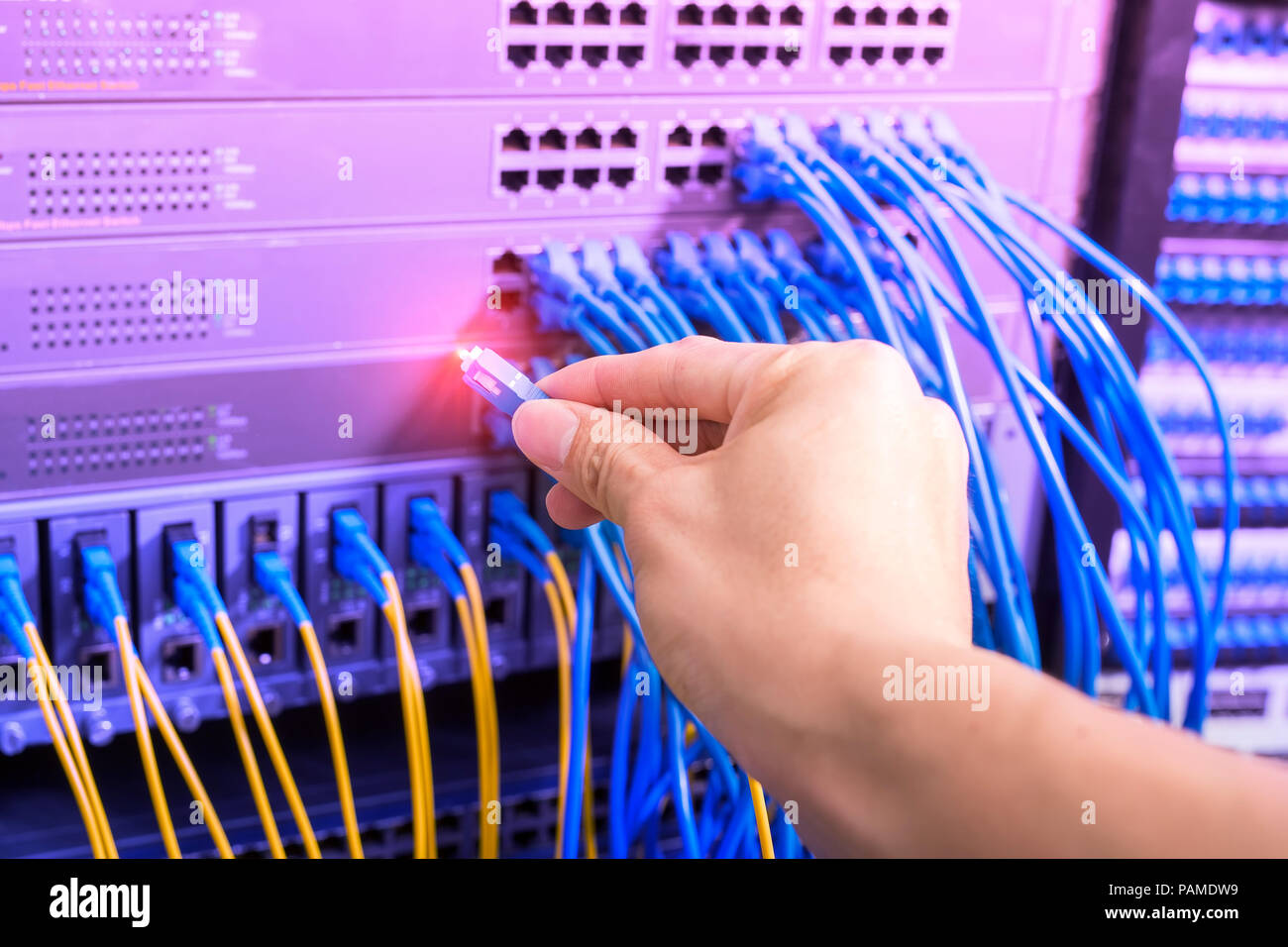 hand with network cables connected to servers in datacenter Stock Photo