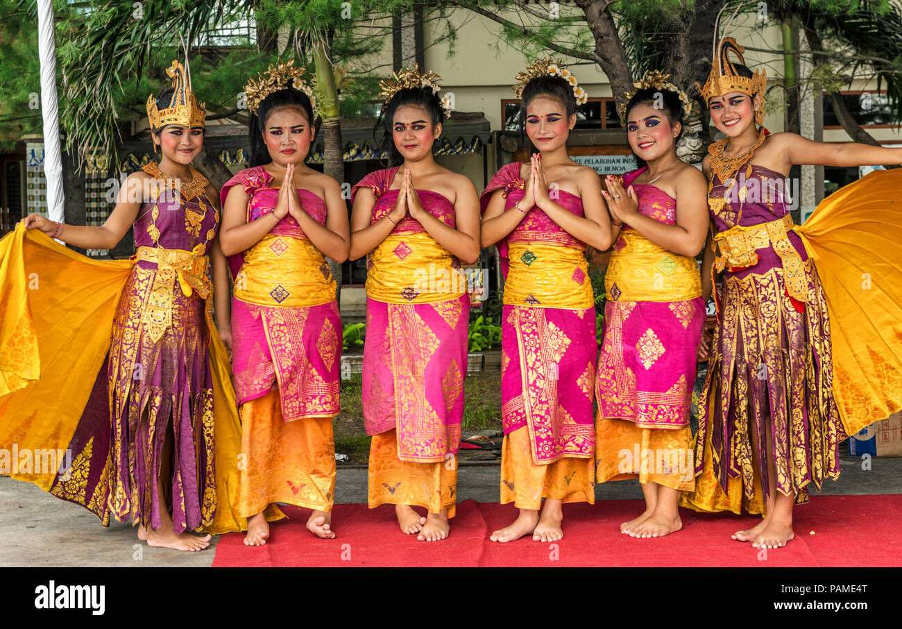 Benoa, Bali, Indonesia - January 2, 2018: Local girls in traditional dresses with ornate gold head-dresses greeting people in Benoa, Bali. Stock Photo