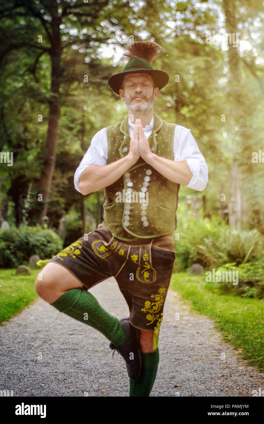 bavarian man standing outdoors in yoga position and meditating Stock Photo
