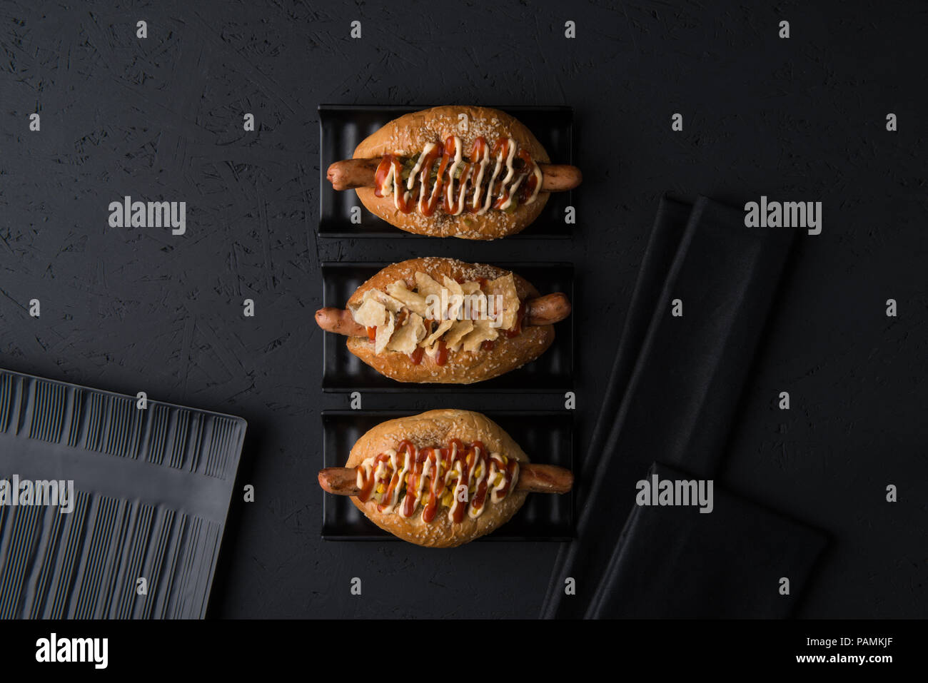 set of hamburgers on flat plates on black background, top view Stock Photo