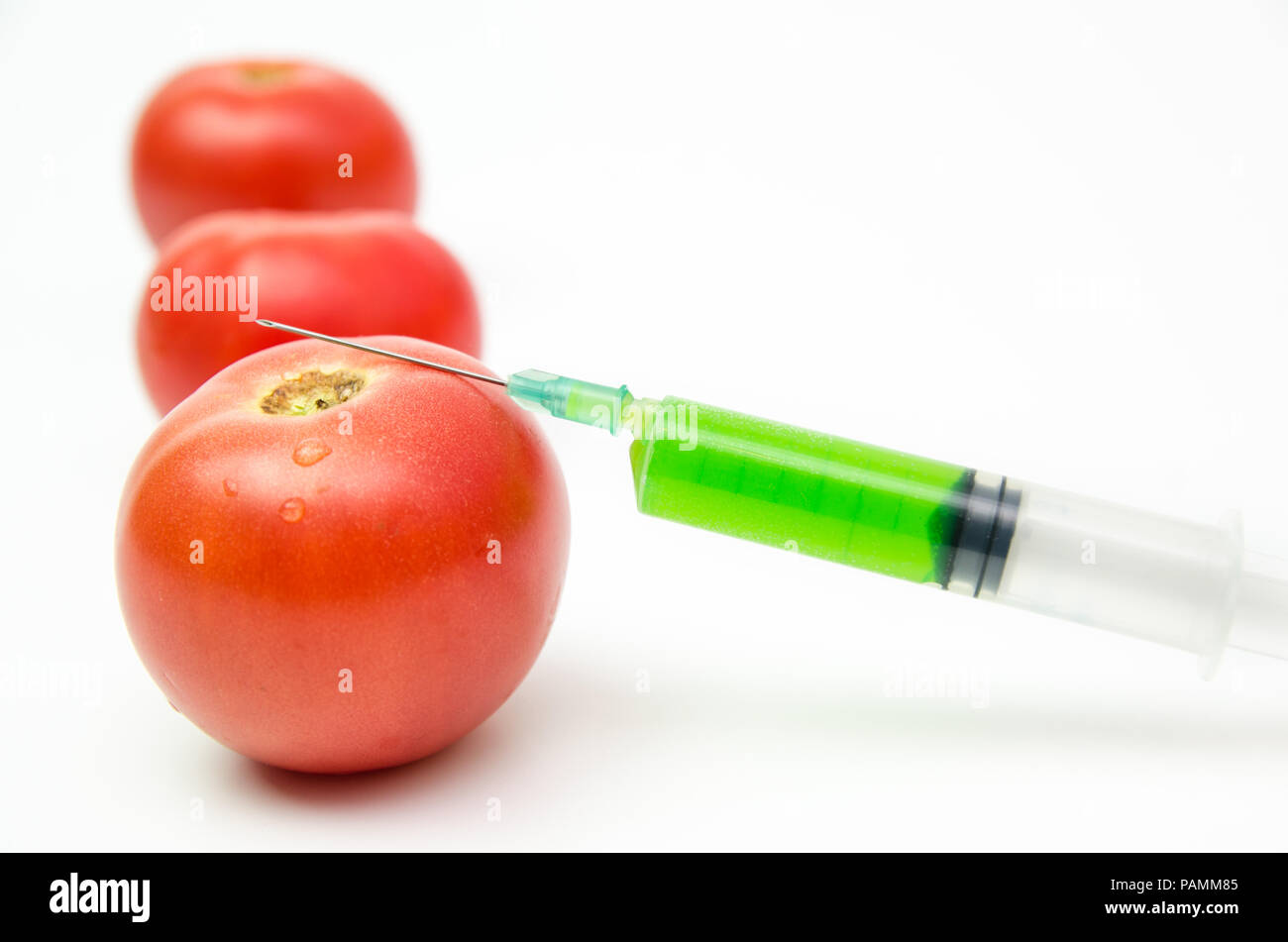 Toxic syringe on some fresh tomatoes indicating dna modification Stock Photo