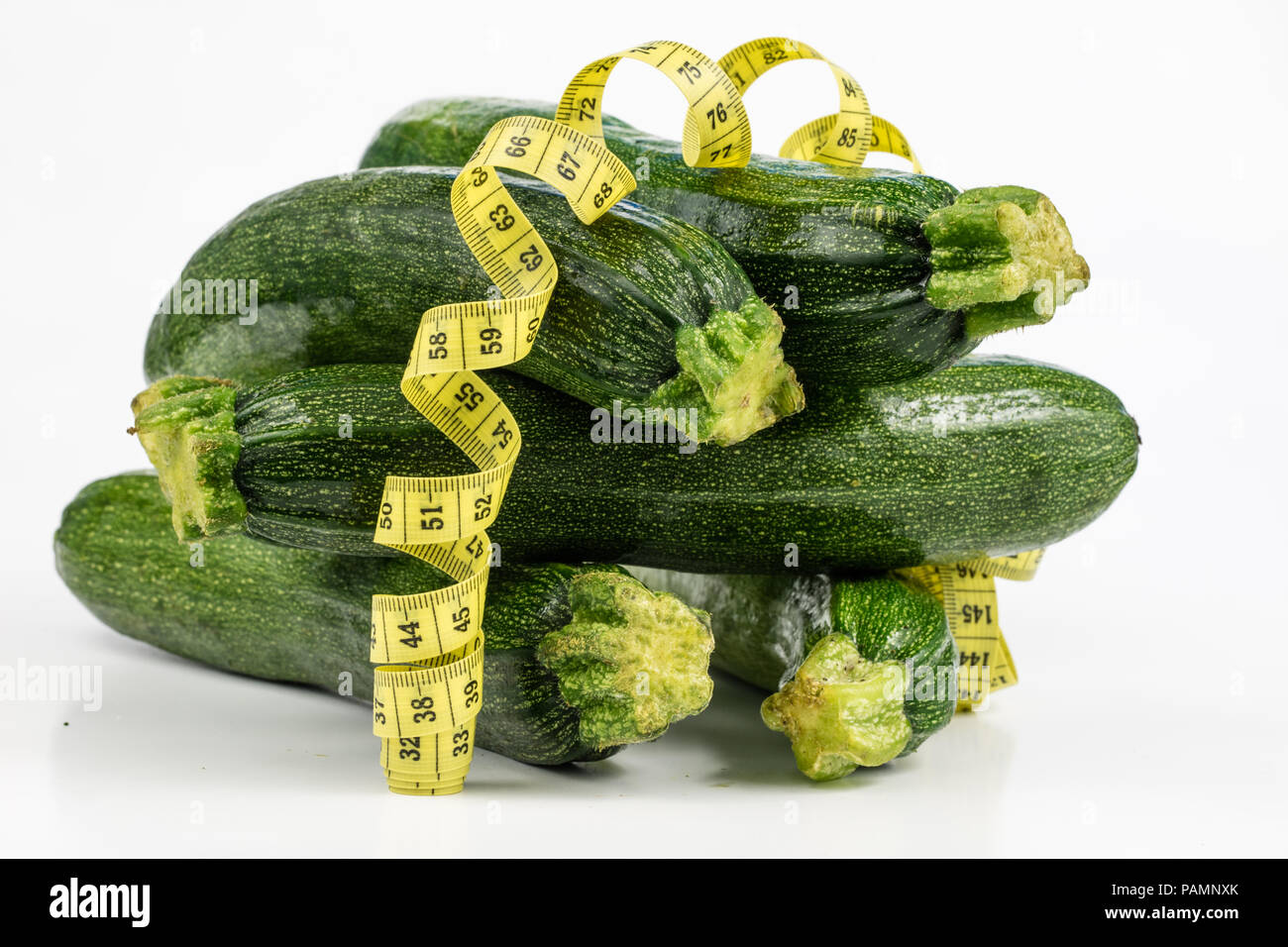 Zucchini on a white table. Tailor measure to measure the waist circumference during the diet