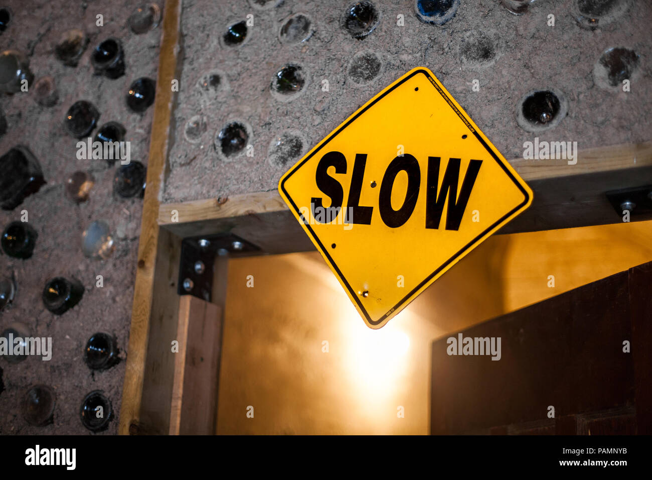 SLOW Sign fixed on an indoors doorframe. Homemade cob walls inlaid
