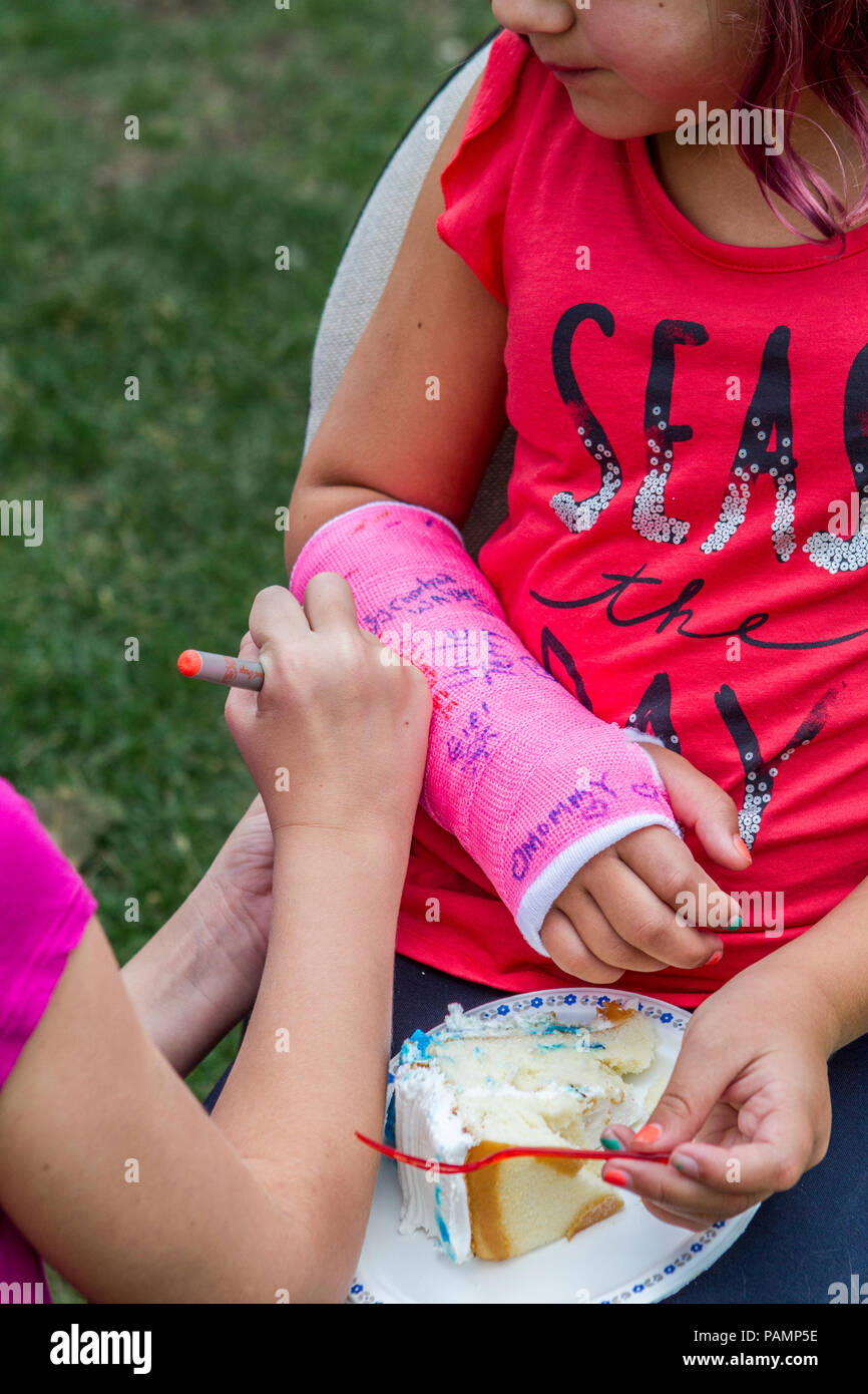 Photo of young girl and right arm is in pink cast., having friend sign it.  Model Release #114 Stock Photo - Alamy