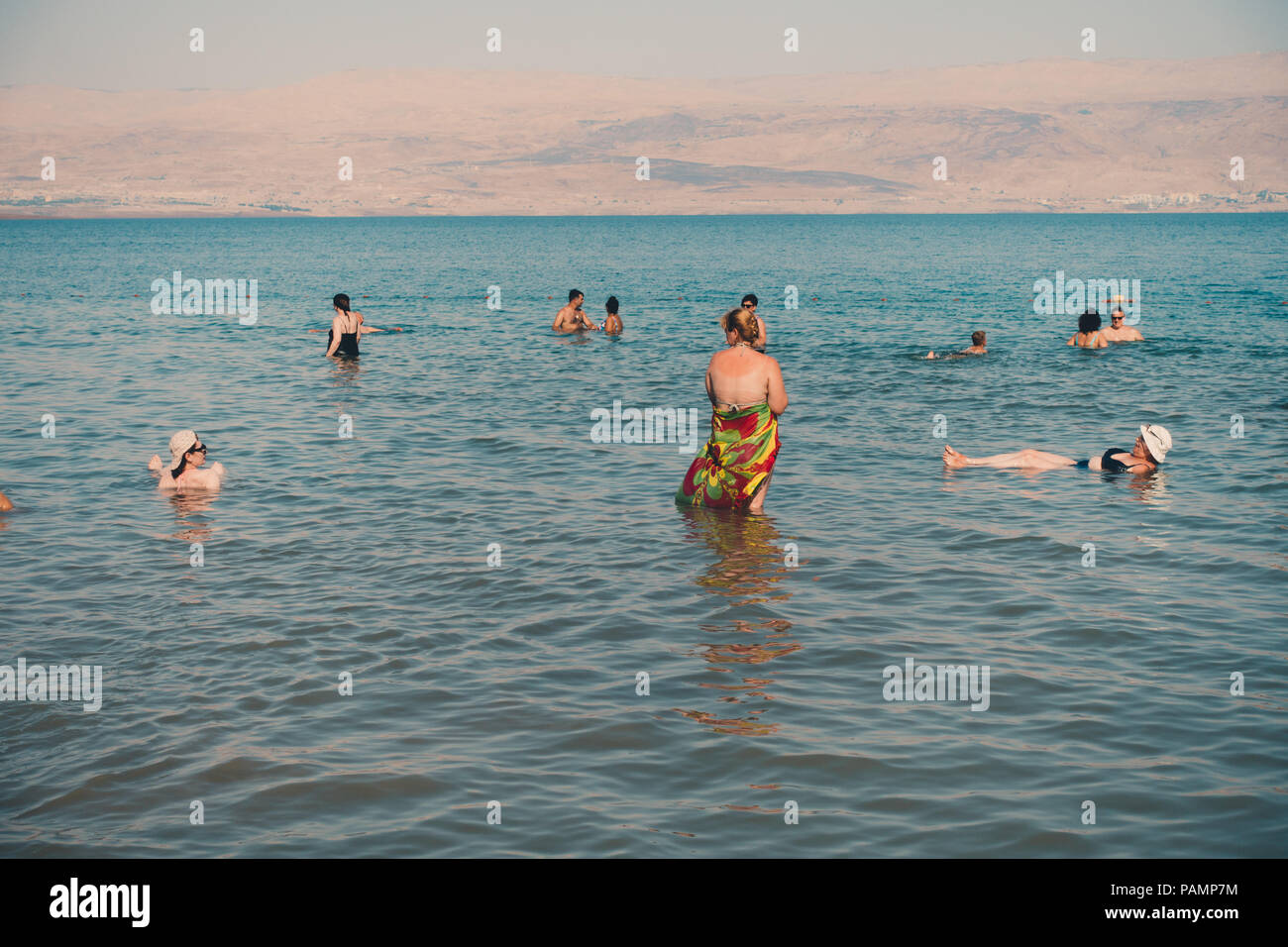 Tourists relax, swim and float in the Dead Sea, Israel, which is so salty it's impossible for a human body to sink Stock Photo