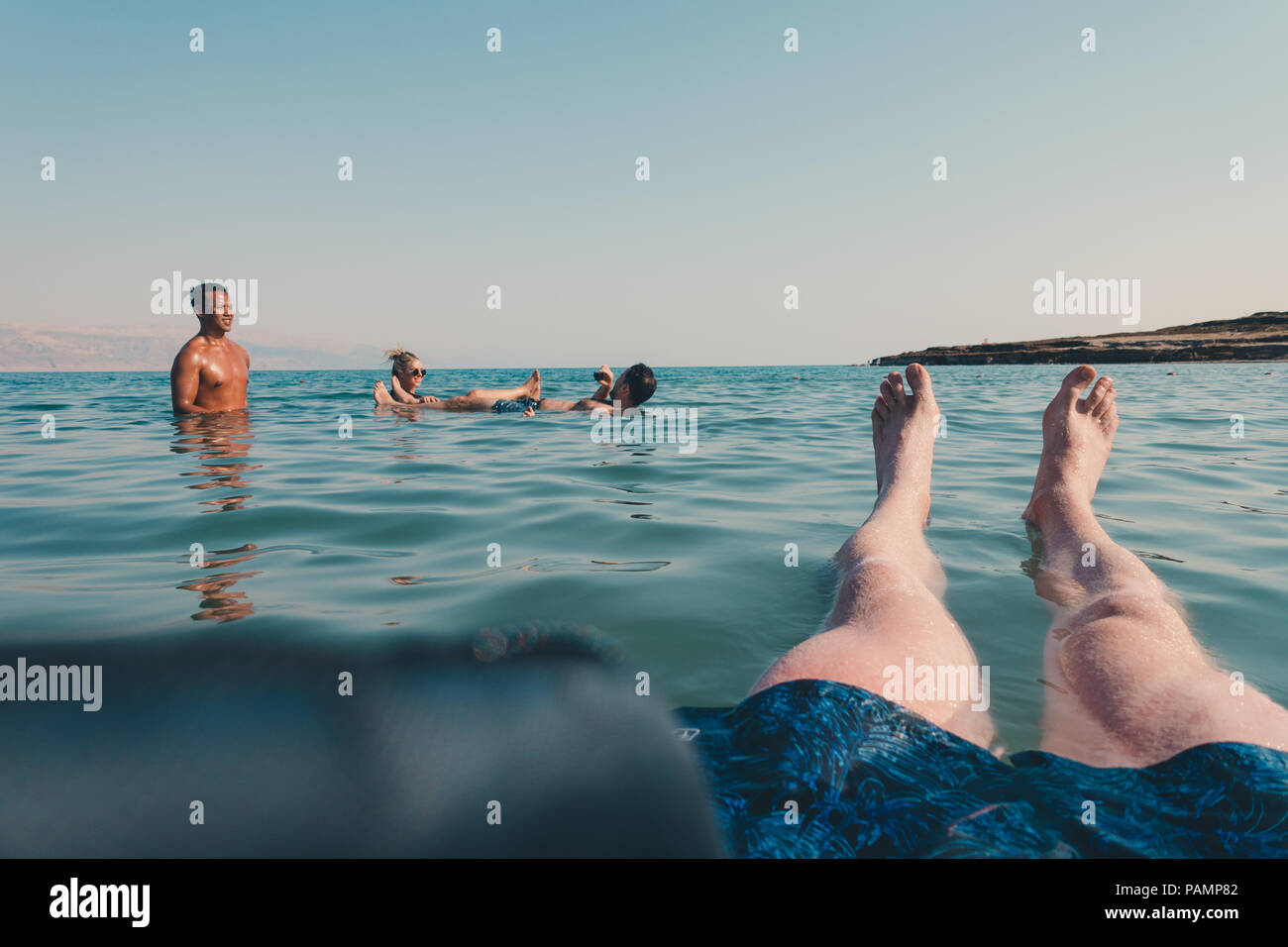 Tourists relax, swim and float in the Dead Sea, Israel, which is so salty it's impossible for a human body to sink Stock Photo